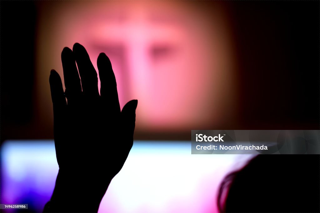 Silhouette hand raising, blurred christian cross background Religion Interior Catholicism Stock Photo