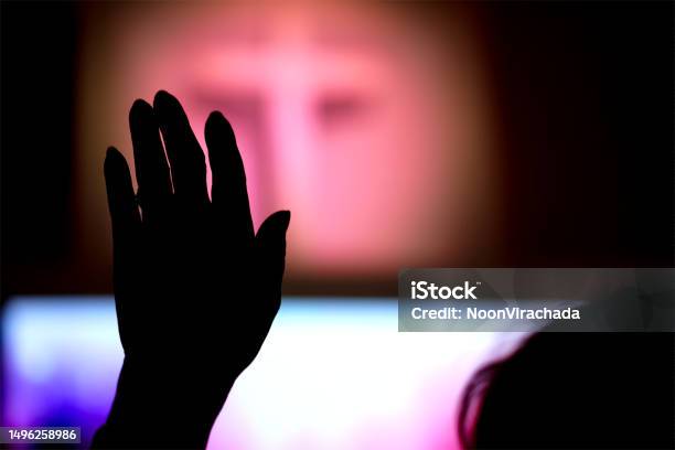Silhouette Hand Raising Blurred Christian Cross Background Stock Photo - Download Image Now