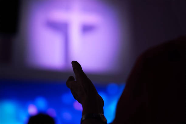 istock Silhouette Hand raising, blurred christian cross background 1496258989