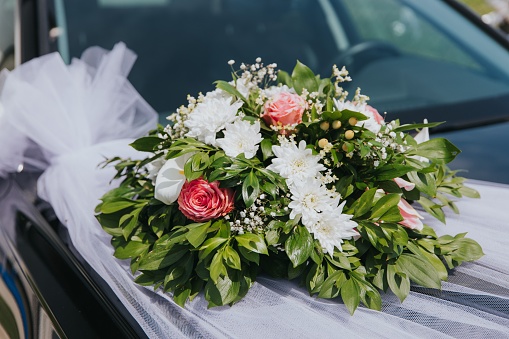 Flower decor on black car. Wedding car with beautiful decorations.