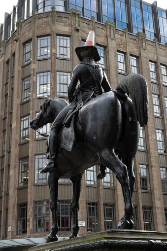 Glasgow, Scotland_February 28,2023.\nStatue of the Duke of Wellington in central Glasgow. Some years back students placed a road stop cone on his head to show their dislike of the English and the cone has remained ever since, becoming a tourist attraction.