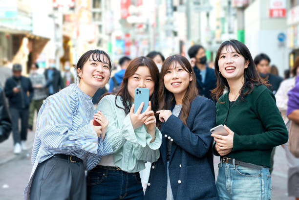 mujeres jóvenes que usan teléfonos inteligentes en la ciudad - k pop fotografías e imágenes de stock