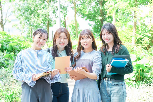 Four young women smiling outdoors on a sunny day