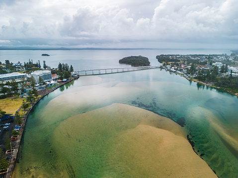Drone view of holiday town with crystal clear water, sand islands and Ferris wheel. The bridge connects two parts of town. Storm is approaching in the background.