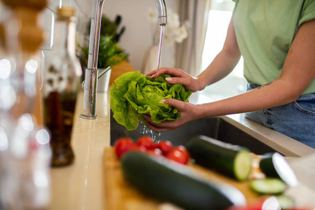 istock Young woman washing and preparing vegetables in the kitchen 1496267842