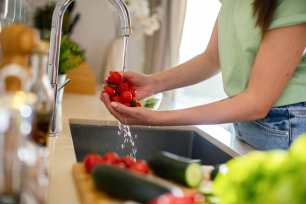 istock Young woman washing and preparing vegetables in the kitchen 1496268510