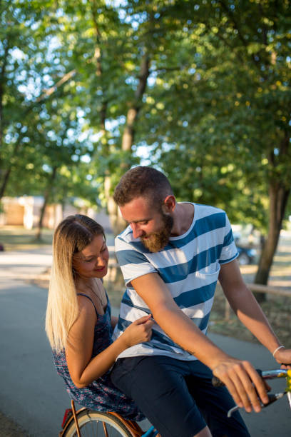 istock Young couple riding bicycle outdoors at the park 1496273072