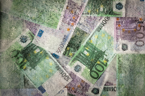 Blurred and defocused photo of one hundred and five hundred euros are defrosted in ice. The European cash currency is frozen.