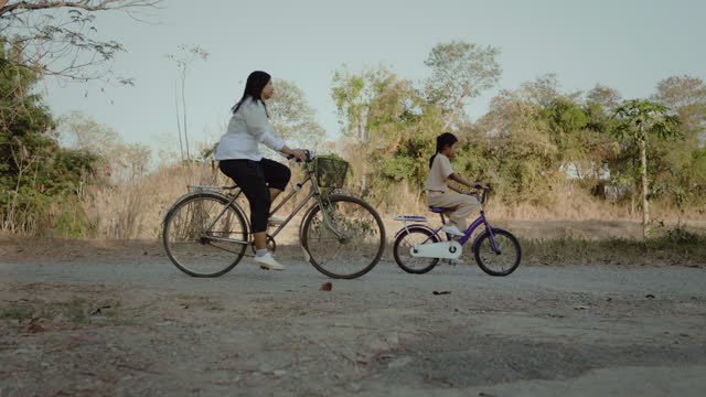 Asian mother and daughter riding a bicycle together.