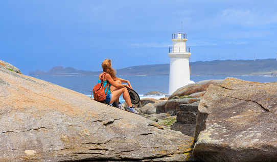 Traveler woman looking at lighthouse- Muxia in Spain