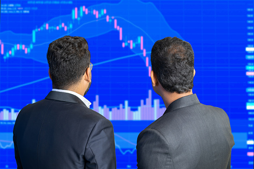 Two stock market trader looks at screen shows candlesticks chart graphic going down, Financial market Crash. Crypto and forex trading.