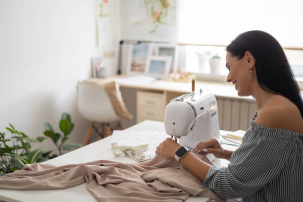 istock Smiling woman skilled tailor clothes manufacture process on sewing machine posing at workplace 1496296058