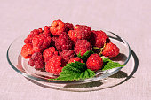 Red raspberry in a plate on the kitchen table, summer seasonal food. Background of fruity ripe berries