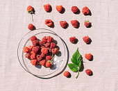 Red raspberry in a plate on the kitchen table, summer seasonal food, bright sunlight and shadows. Background of fruity ripe berrie