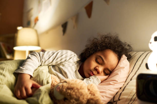 Little boy sleeping in bed with toy stock photo