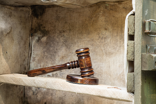 The judge's gavel stands on a wooden ammo box, military tribunal, court