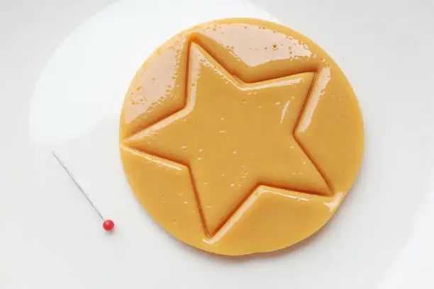 Photo of Dalgona candy or Ppopgi. Sugar Honeycomb cookie with star shape and needle on white plate. candy challenge