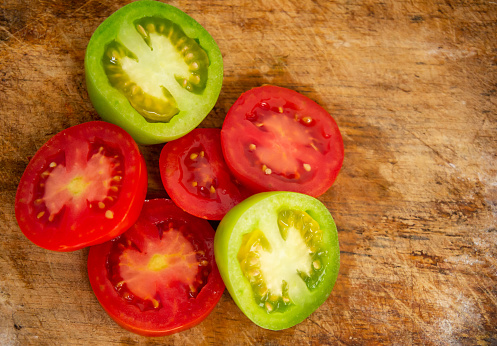 sliced ​​fresh tomatoes full of vitamins on a wooden chopping board background