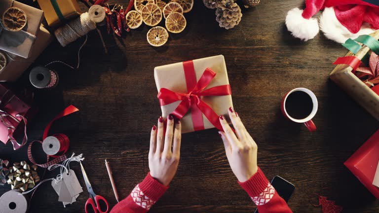 Top view woman wrapping christmas presents at wooden desk hands from above - Red Epic Dragon