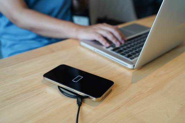 istock Charging mobile phone battery with wireless charging device in the table. Smartphone charging on a charging pad. Mobile phone near wireless charger Modern lifestyle technology concept 1496309515