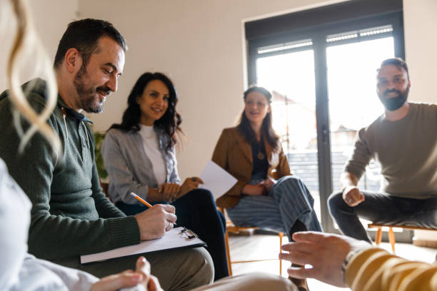 istock Male therapist writing notes on the clipboard during a group therapy session 1496311879