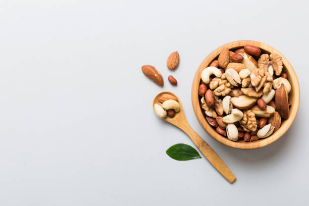 istock mixed nuts in bowl. Mix of various nuts on colored background. pistachios, cashews, walnuts, hazelnuts, peanuts and brazil nuts 1496314583