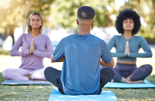 Mediation, coaching and yoga class with people in park for relax, mindfulness and spirituality. Zen, fitness and wellness with group and training in grass field for health, healing or gratitude