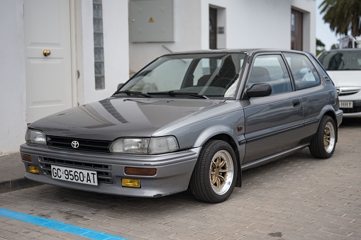 Tirajana, Spain – May 28, 2023: A classic Japanese car, the small Toyota Corolla XL EE90 in gray color parked in the street