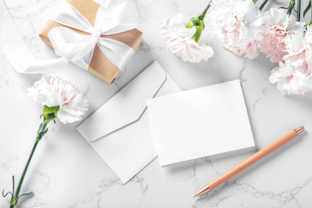 istock Blank card and envelop with pen, flowers and gift box on marble background 1496321814