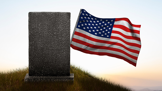 Tombstone with an American flag on the cemetery. Memorial day concept