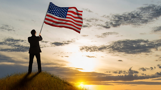 Rear view of a businessman holding the American national flag. Memorial day concept