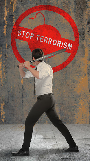 Rear view of a businessman holding a baseball bat with a stop terrorism sign on the wall