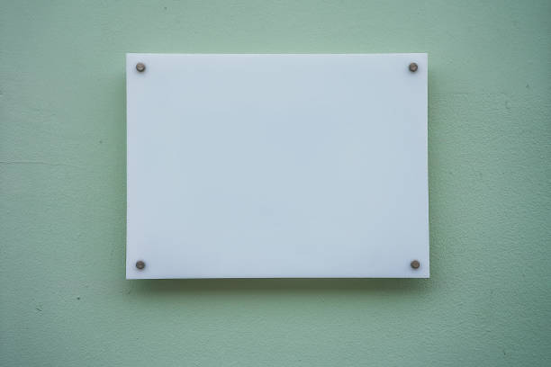White nameplate on spacer metal holders mounted on office building White glass nameplate on spacer metal holders mounted on office building wall outside. Clear printing board for branding with mockup space. store wall surrounding wall facade stock pictures, royalty-free photos & images