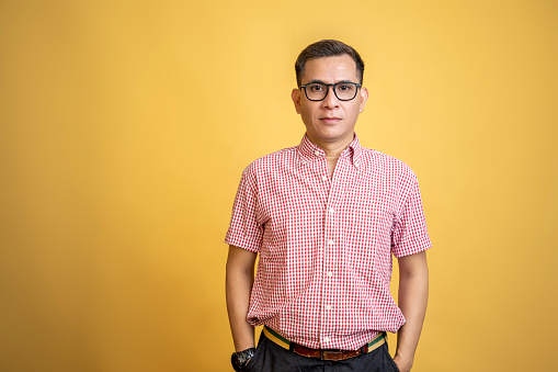 Man with eyeglasses and a shirt standing on a colored background