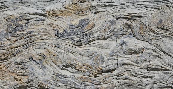 Texture of gray stone with layers and lines  for background and pattern. Gray and yellow grunge banner. Beautiful stone texture made by wind and sea