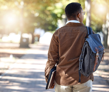 Black man, walking or backpack on campus, park nature or garden for college, university or school studying development. Student, gen z and person with learning books, education bag or growth mindset