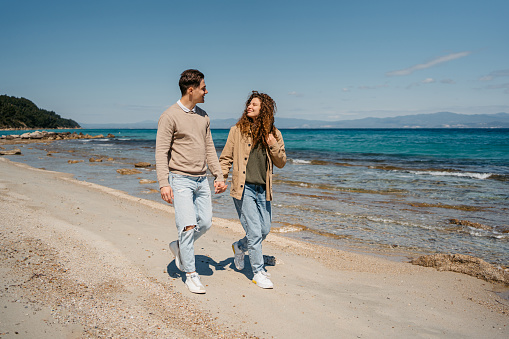 Beautiful young couple walking on the beach in Afitos, Greece.