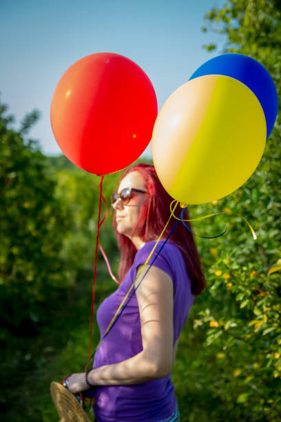 woman on grassland with colored balloons