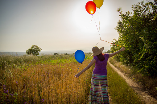 woman on grassland with colored balloons