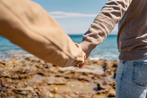 Beautiful young couple holding hands on the beach in Afitos, Greece. Close-up.