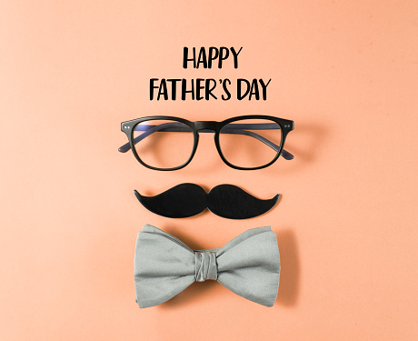 Happy Father's Day concept with eye glasses, bow tie and mustache paper on orange background