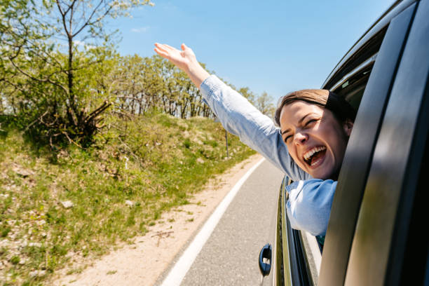istock Young Woman Sticking Her Head Out The Car Window 1496339792