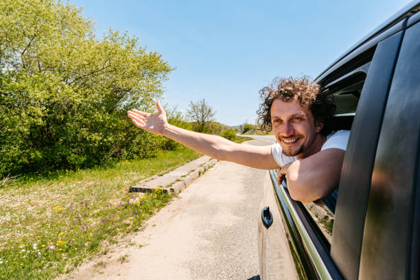 istock Young Man Sticking His Head Out The Car Window 1496339851