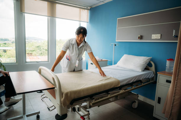 An Asian female nurse making the bed at a hospital ward stock photo