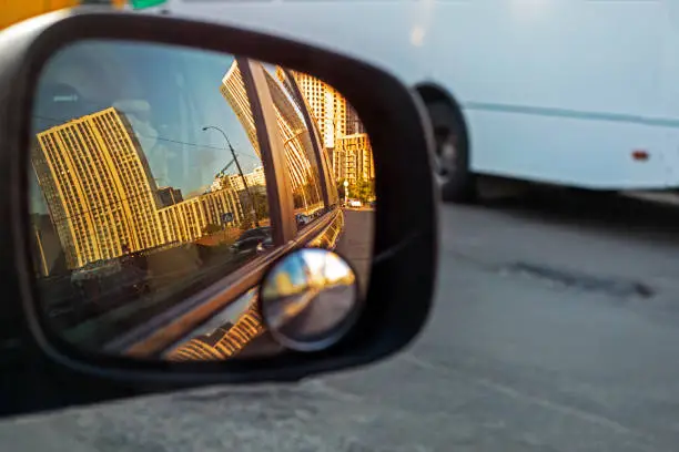 view of the sky in the right side car mirror in the evening at sunset. Traffic jam in the city