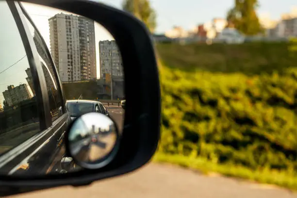 view of the city in the right side car mirror in the evening at sunset. Traffic jam in the city