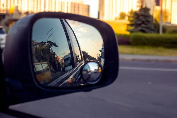 view of the sky in the right side car mirror in the evening at sunset. Traffic jam in the city