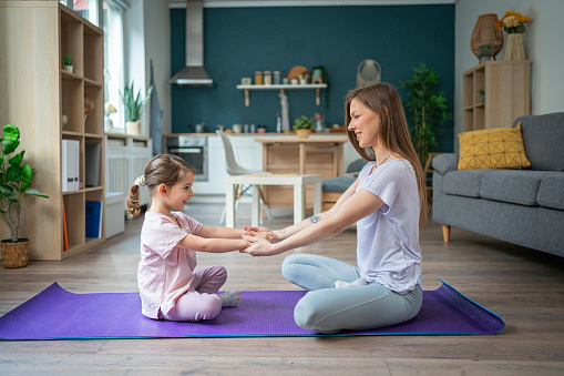 Active and healthy young Caucasian woman, doing home workout with her daughter