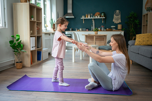 Active and healthy young Caucasian woman, doing home workout with her daughter