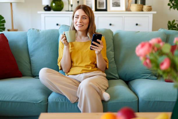 istock Woman using smartphone while drinking coffee at her home in the morning 1496345169